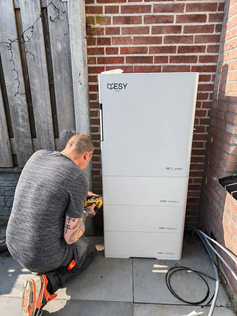 An outdoor white battery storage unit next to a house, used for storing renewable energy for residential use.