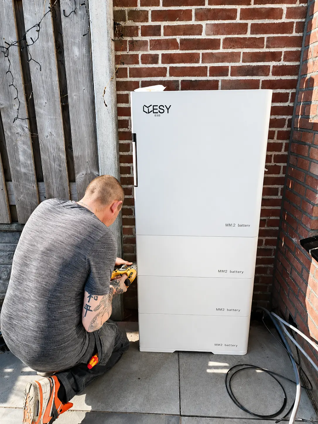 An outdoor white battery storage unit next to a house, used for storing renewable energy for residential use.